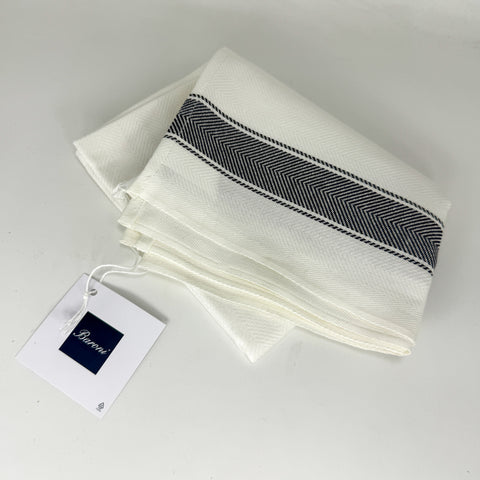 A folded white woven textile with a wide black herringbone stripe across the center, shown on a light gray background with a branded paper tag attached.