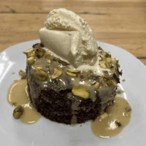 Sticky Toffee Pudding topped with chopped pistachios and vanilla ice cream